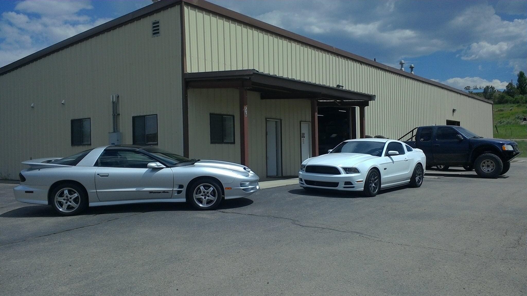 Doug's Auto Body shop building with cars parked out front on a sunny day