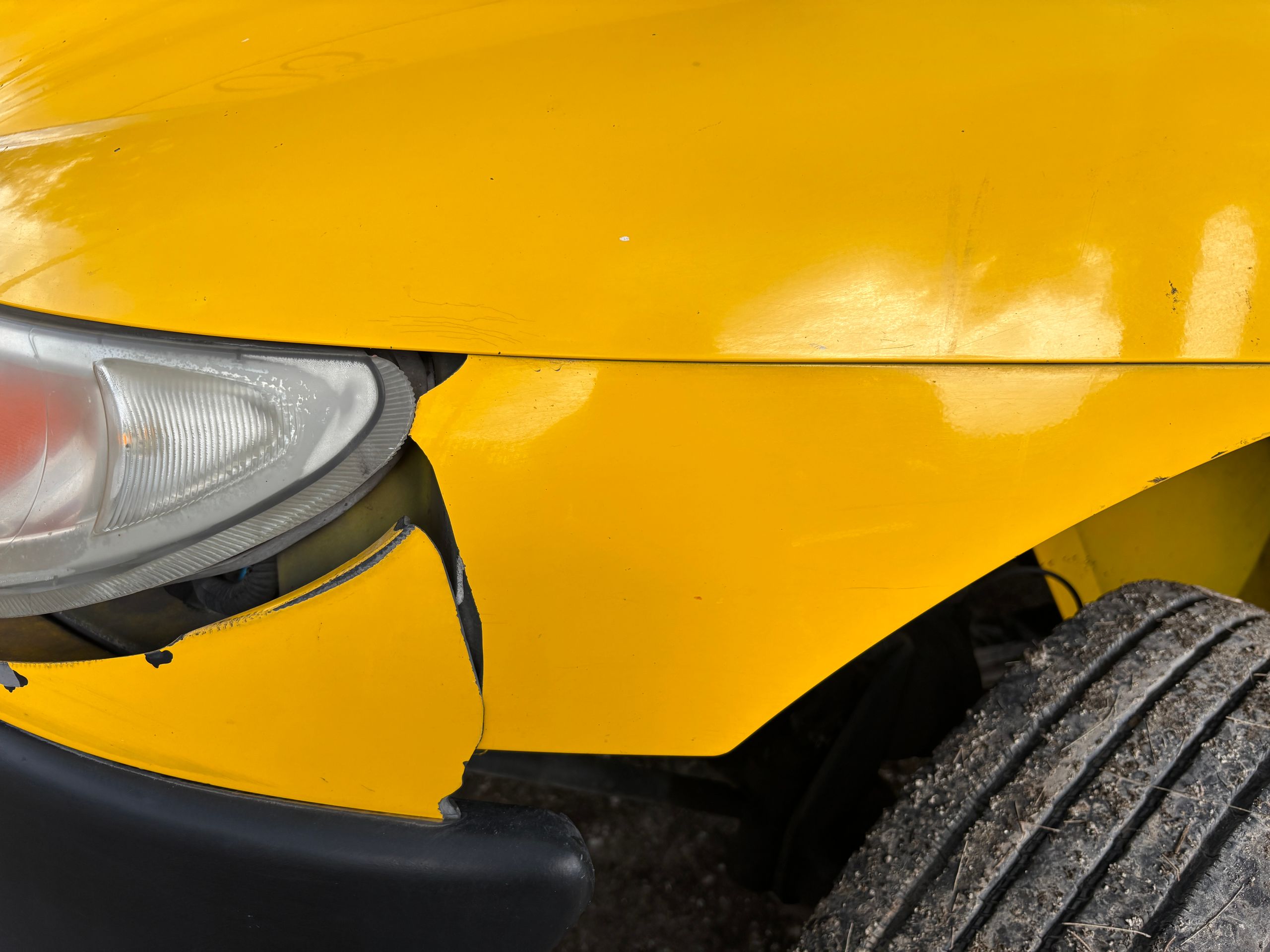Close-up of front-end collision damage on a yellow car, ready for an estimate