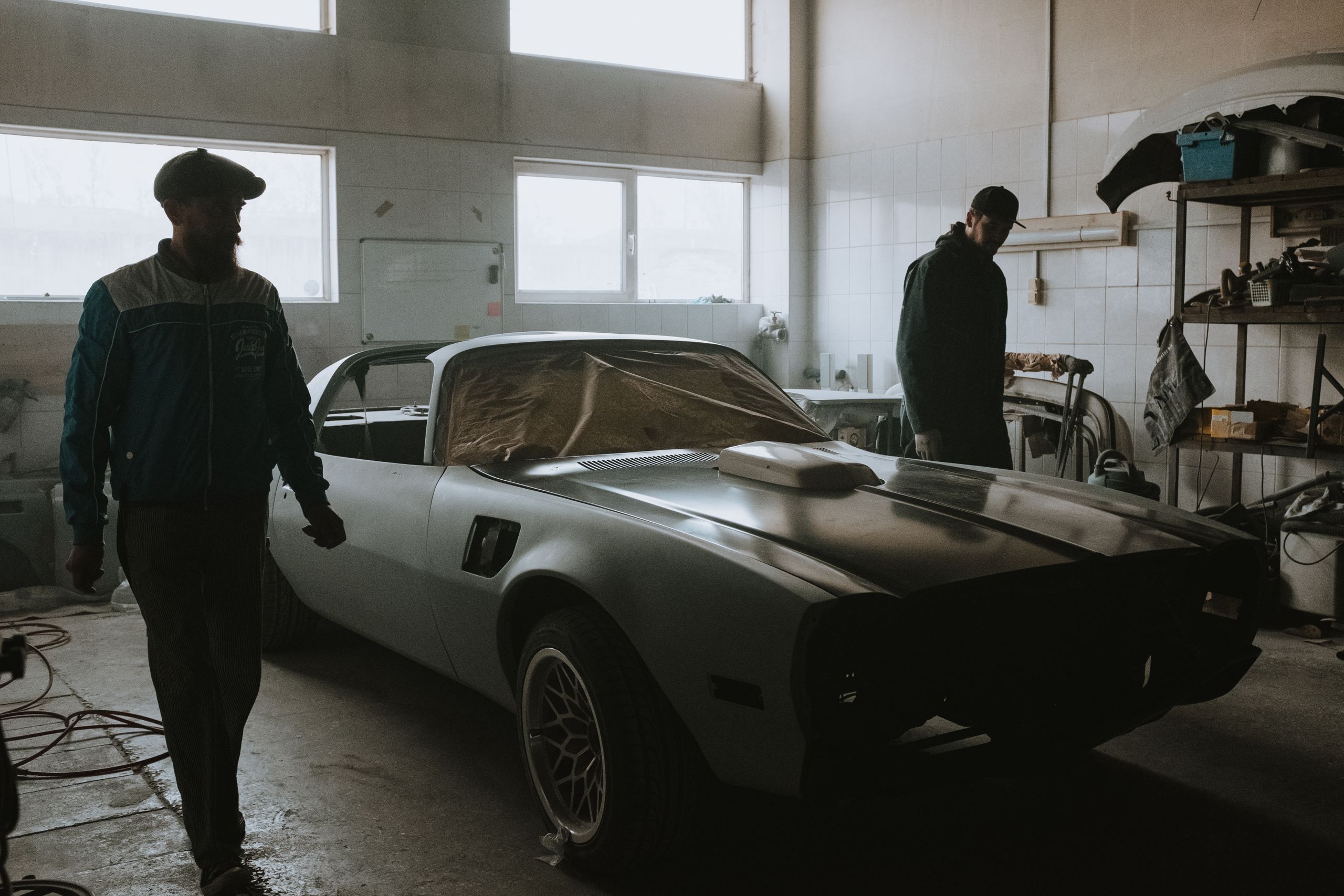 Technicians working on a classic Pontiac in an auto body workshop