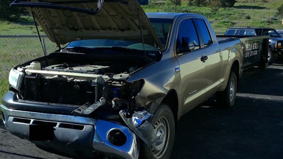 A Toyota Tundra with front-end collision damage and the hood up, before repair